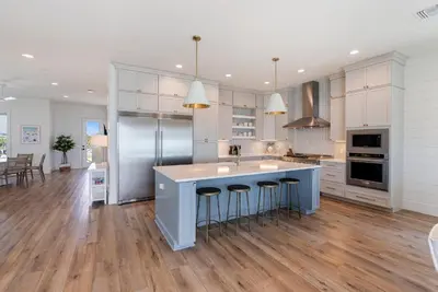 a kitchen with white cabinets and a island with bar stools at Wine Down in Panama City Beach