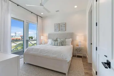 a white bedroom with a bed and a large window at Wine Down in Panama City Beach