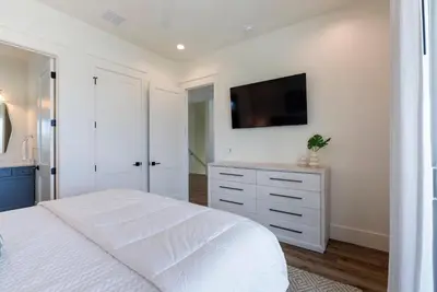 a bedroom with a white bed and a tv on the wall at Wine Down in Panama City Beach