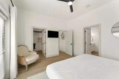a white bedroom with a bed and a chair at Somerset by the Sea by Travel Life Vacations in Santa Rosa Beach