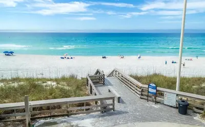 a boardwalk leading to a beach with people on it at Luxury by the Sea by Travel Life Vacations in Santa Rosa Beach