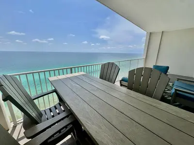 a wooden table and chairs on a balcony with the ocean at Ocean Reef 2203 by Emerald Coast Retreats in Panama City Beach