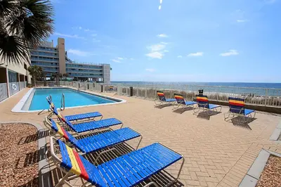 a row of blue lounge chairs next to a swimming pool at Ocean Reef 2203 by Emerald Coast Retreats in Panama City Beach