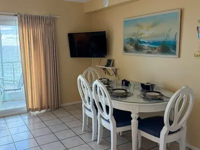a dining room with a table and chairs and a television at The Summit 830 - Ocean Front Condo in Panama City Beach