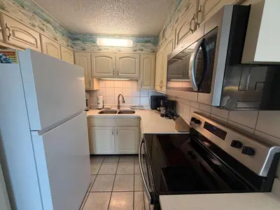 a kitchen with a white refrigerator and a sink at The Summit 830 - Ocean Front Condo in Panama City Beach