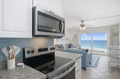 a kitchen with a stove top oven next to a living room at The Summit 926 - One Bedroom Beachfront Condo in Panama City Beach