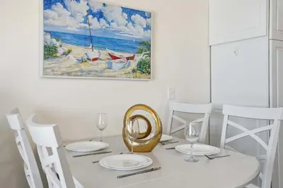 a dining room table with white chairs and a painting at The Summit 926 - One Bedroom Beachfront Condo in Panama City Beach