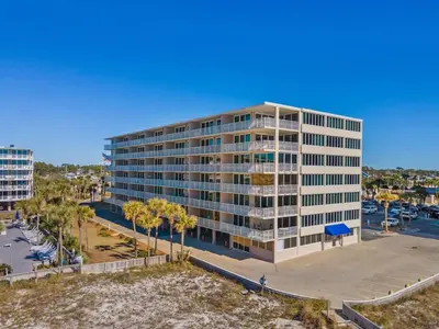 an apartment building with palm trees in front of a harbor at Dunes of Panama C104 - First Floor Gem in Panama City Beach