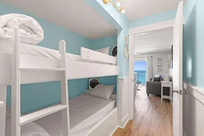 a bedroom with two bunk beds with a blue wall at The Summit 1419 - Gulf View Escape in Panama City Beach