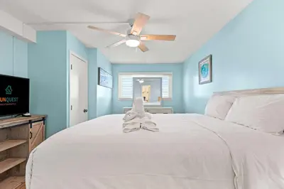 a bedroom with a white bed with a ceiling fan at The Summit 1419 - Gulf View Escape in Panama City Beach