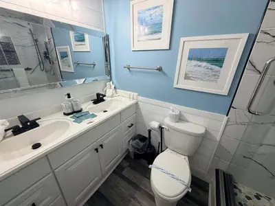 a bathroom with a toilet and a sink and a mirror at The Summit 1132 - Beachfront Bliss Stunning 2BR in Panama City Beach