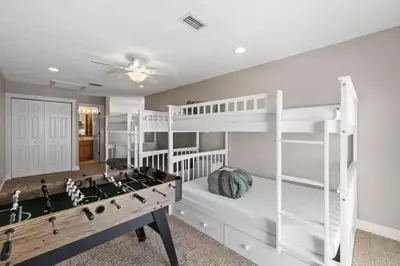 a bedroom with white bunk beds and a pool table at Beach Access - Pool - Game Room - Pets - BBQ Grill in Panama City Beach