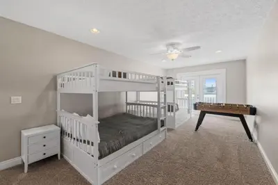 a bedroom with two bunk beds and a table at Beach Access - Pool - Game Room - Pets - BBQ Grill in Panama City Beach