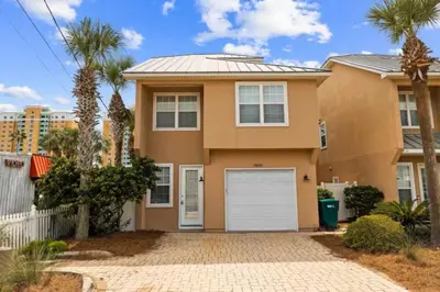 a house with palm trees in front of it at Beach Access - Pool - Game Room - Pets - BBQ Grill in Panama City Beach
