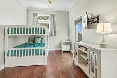 a white room with a bunk bed and a desk at Walk to the Beach - BBQ - Patio - Play Area - Pets in Panama City Beach