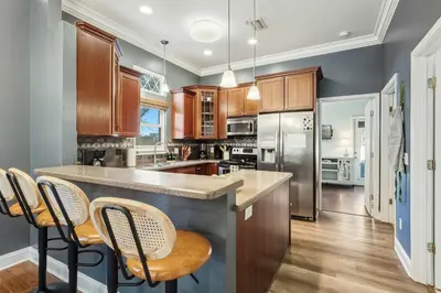 a kitchen with wooden cabinets and a island with bar stools at Walk to the Beach - BBQ - Patio - Play Area - Pets in Panama City Beach
