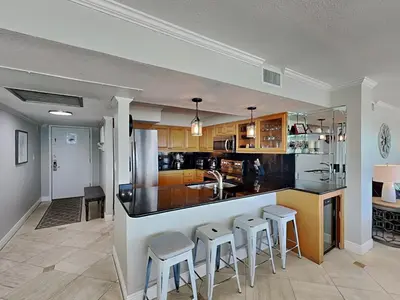 a kitchen with a counter and stools in a room at Dunes of Panama #D801 in Panama City Beach