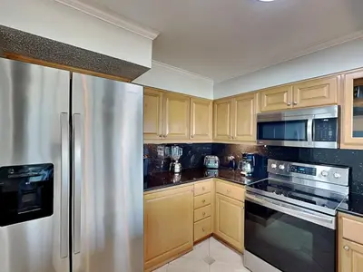 a kitchen with wooden cabinets and a stainless steel refrigerator at Dunes of Panama #D801 in Panama City Beach