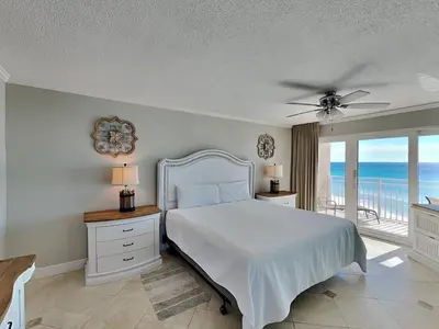 a bedroom with a bed and a balcony with the ocean at Dunes of Panama #D801 in Panama City Beach