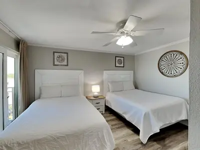 two beds in a bedroom with a ceiling fan at Dunes of Panama #D801 in Panama City Beach