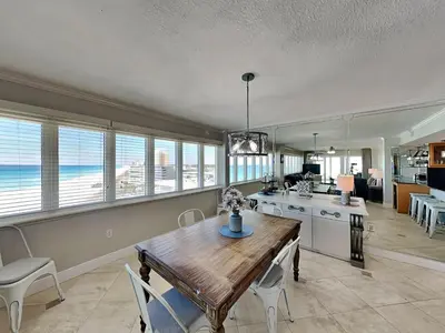 a dining room with a table and a kitchen with the ocean at Dunes of Panama #D801 in Panama City Beach