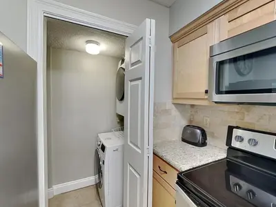 a small kitchen with a stove and a microwave at Dunes of Panama #E1405 in Panama City Beach