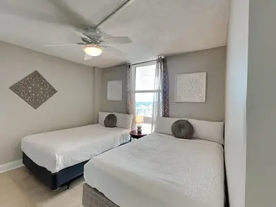 two beds in a bedroom with a ceiling fan at Dunes of Panama #E1405 in Panama City Beach