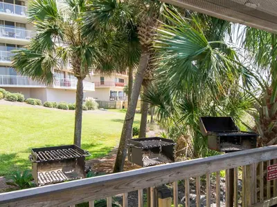 a balcony with palm trees and benches and a building at Dunes of Panama #E1405 in Panama City Beach