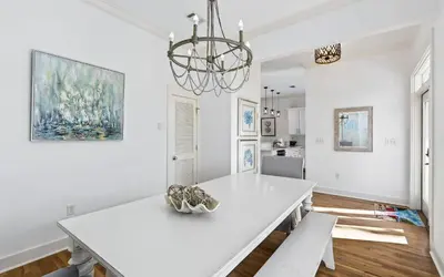 a white dining room with a table and a chandelier at A Villa La La in Santa Rosa Beach