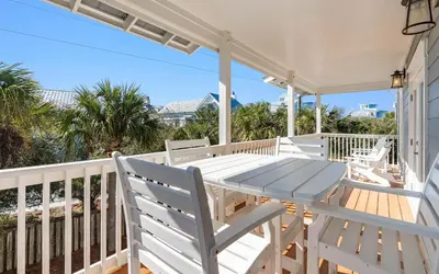 a white porch with a table and chairs on it at A Villa La La in Santa Rosa Beach