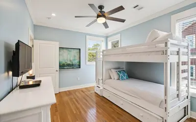 a bedroom with a white bunk bed and a ceiling fan at A Villa La La in Santa Rosa Beach