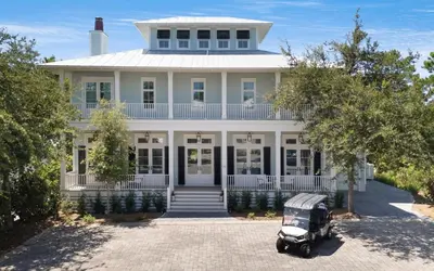 an old car parked in front of a white house at APRÉS 30A in Santa Rosa Beach