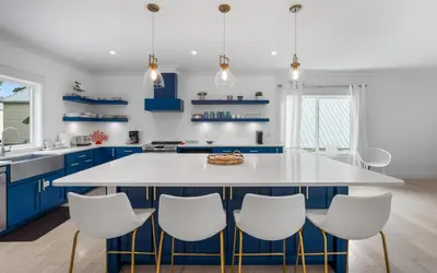 a kitchen with blue cabinets and a white island with white chairs at Barsealona in Santa Rosa Beach