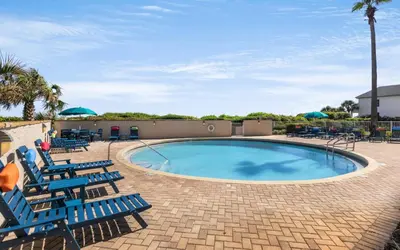 a swimming pool with blue chairs and umbrellas at Beachcrest 202 in Santa Rosa Beach