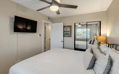 a bedroom with a white bed and a flat screen tv at Beachcrest 202 in Santa Rosa Beach