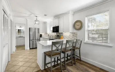 a kitchen with white cabinets and a bar with stools at Beachwood 8G in Santa Rosa Beach