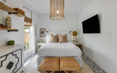 a bedroom with a bed and a tv on the wall at Cottage Breeze in Rosemary Beach