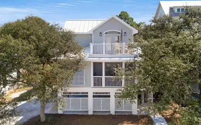 a white house with trees in front of it at Crown Jules in Santa Rosa Beach