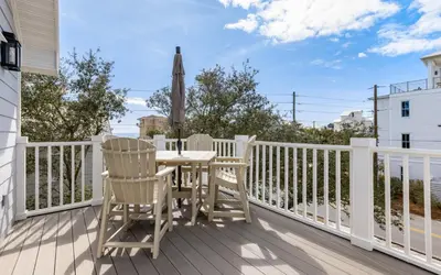 a deck with a table and chairs and an umbrella at Crown Jules in Santa Rosa Beach