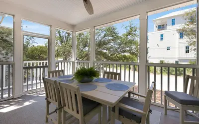 a screened in porch with a table and chairs at Crown Jules in Santa Rosa Beach