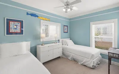 a blue bedroom with two beds and a ceiling fan at Ethridge House in Santa Rosa Beach