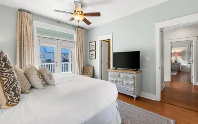 a bedroom with a white bed and a flat screen tv at Four Palms in Santa Rosa Beach