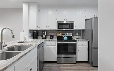 a kitchen with white cabinets and a stainless steel refrigerator at Happy Oasis in Inlet Beach