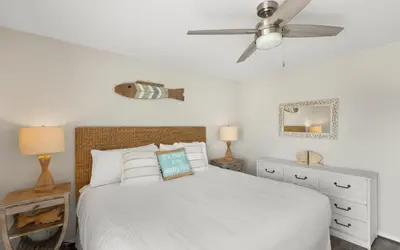 a bedroom with a white bed and a ceiling fan at Happy Oasis in Inlet Beach