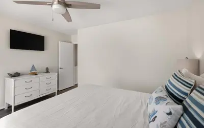 a white bedroom with a bed and a ceiling fan at Happy Oasis in Inlet Beach