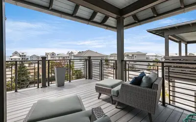 a balcony with a couch and chairs on a deck at Heaven on Pointe in Santa Rosa Beach