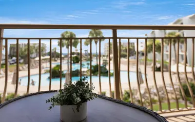 a table with a plant on a balcony with a pool at High Pointe Unit 2-223 in Rosemary Beach