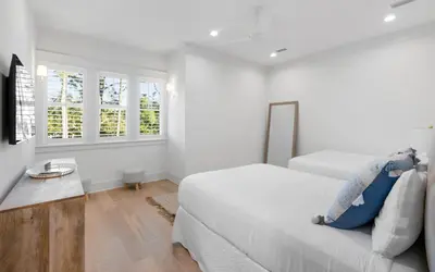 a white bedroom with a bed and two windows at Keepin It Reel in Santa Rosa Beach