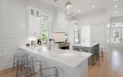 a white kitchen with a large island with bar stools at Keepin It Reel in Santa Rosa Beach