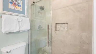 a shower with a glass door in a bathroom at Lemon Drop House in Seacrest